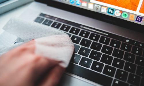 person wiping down keyboard