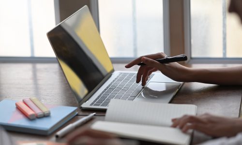 hand on laptop with pen